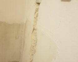 Uszkodzona ściana w łazience wymagająca elektryka.