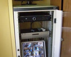 Telewizor osadzony w białej szafce ze zintegrowanym okablowaniem elektrycznym.