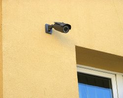 Elektryk zainstalował kamerę bezpieczeństwa z boku budynku.